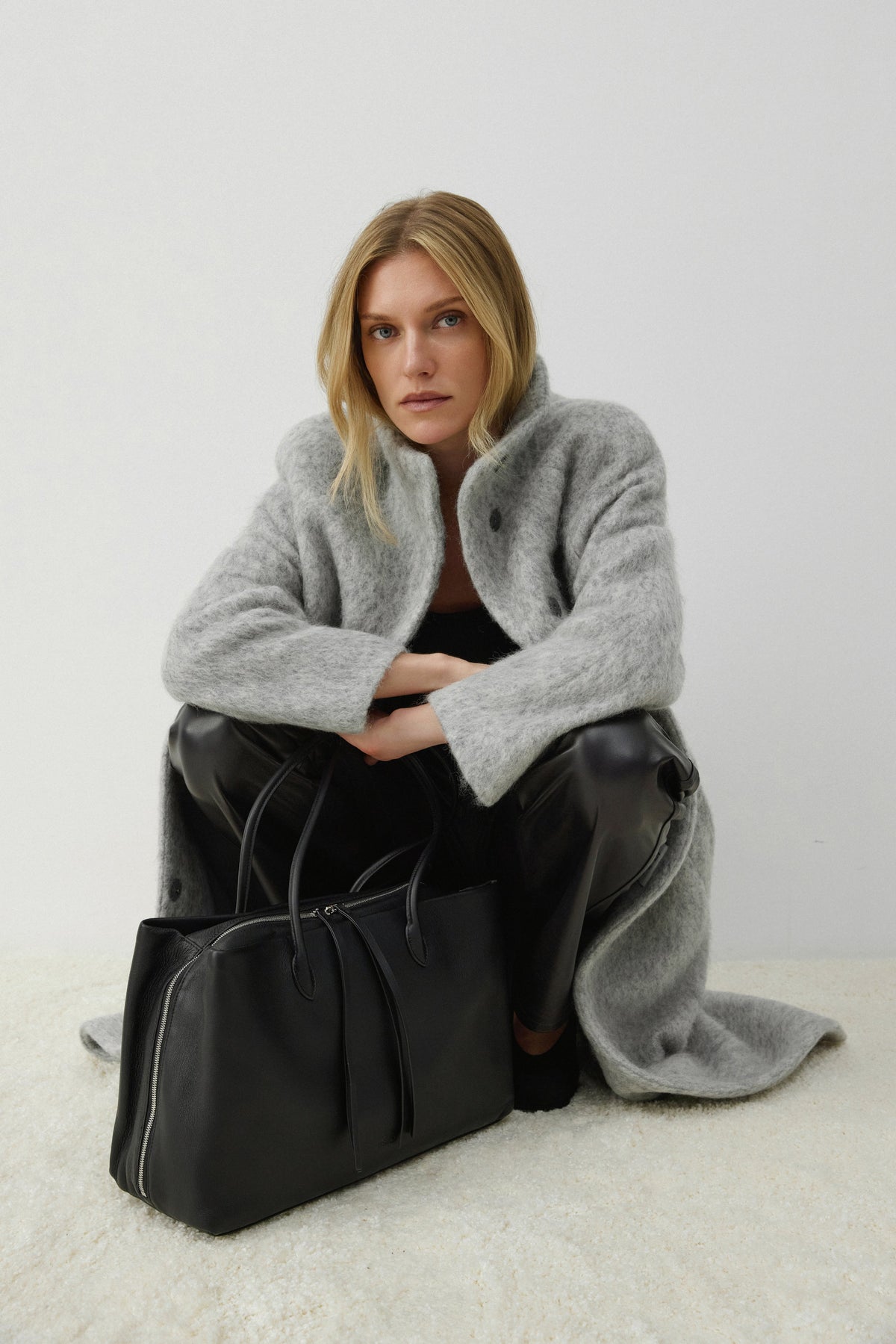 Kniendes Model posiert mit der eleganten schwarzen Leder-Tote-Bag im A4-Format