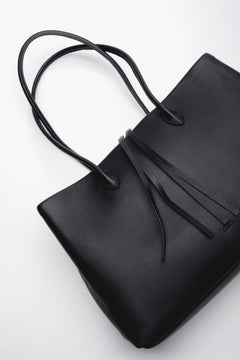 Schräge Draufsicht auf den Reißverschluss und die feinen Lederdetails der schwarzen Handtasche