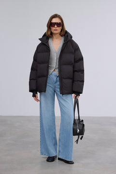 Model präsentiert die offene schwarze Winterjacke im Loose-Fit zu hellen Jeans