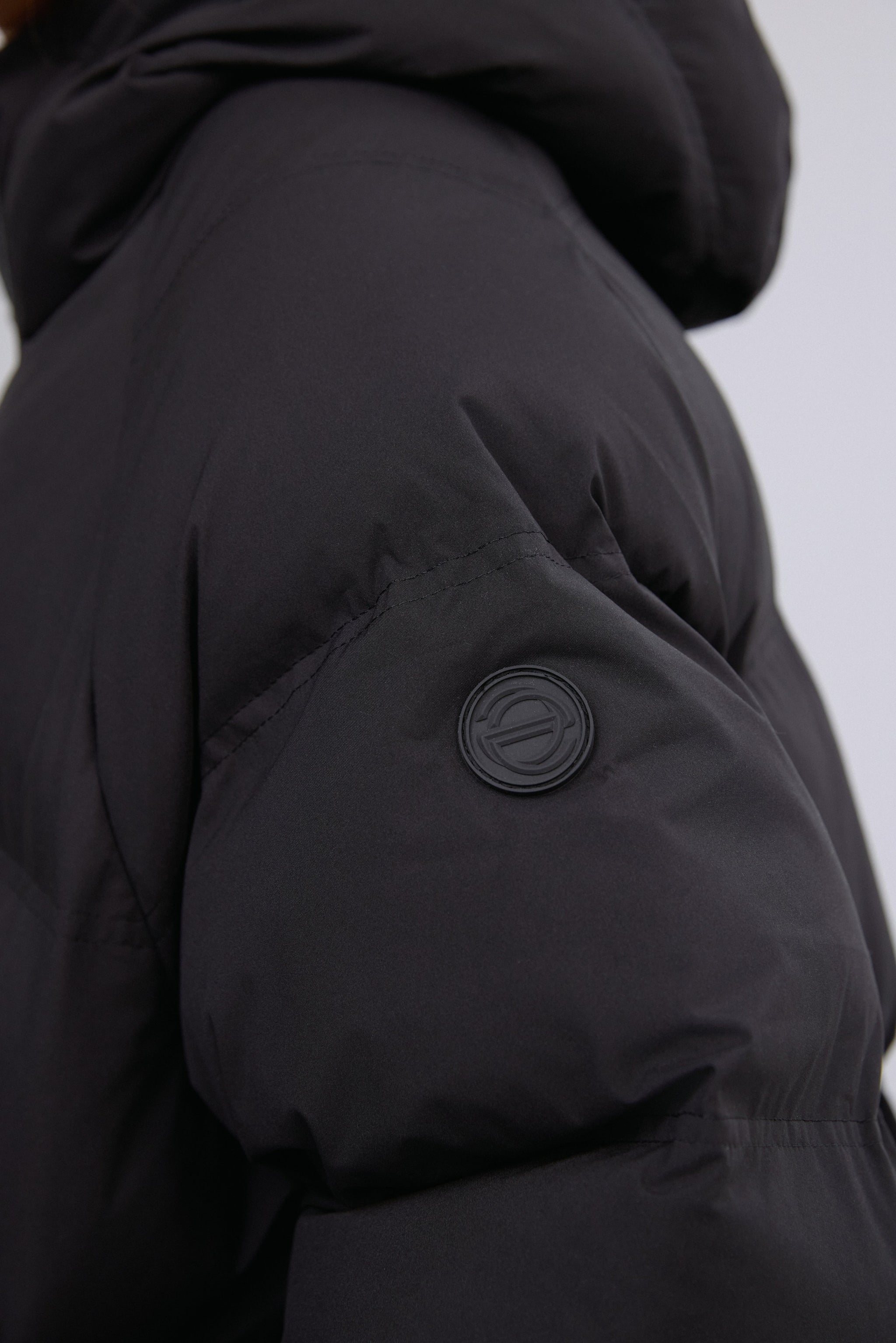 Nahaufnahme des Ärmels der schwarzen Jacke mit dezentem Knopfdetail