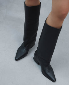 Detailansicht von oben auf die schwarzen Stiefel beim Gehen