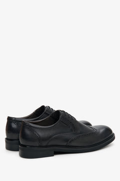 Schräge Rückansicht der schwarzen Herren-Halbschuhe aus Leder mit dekorativer Brogue-Perforation und flachem Absatz   