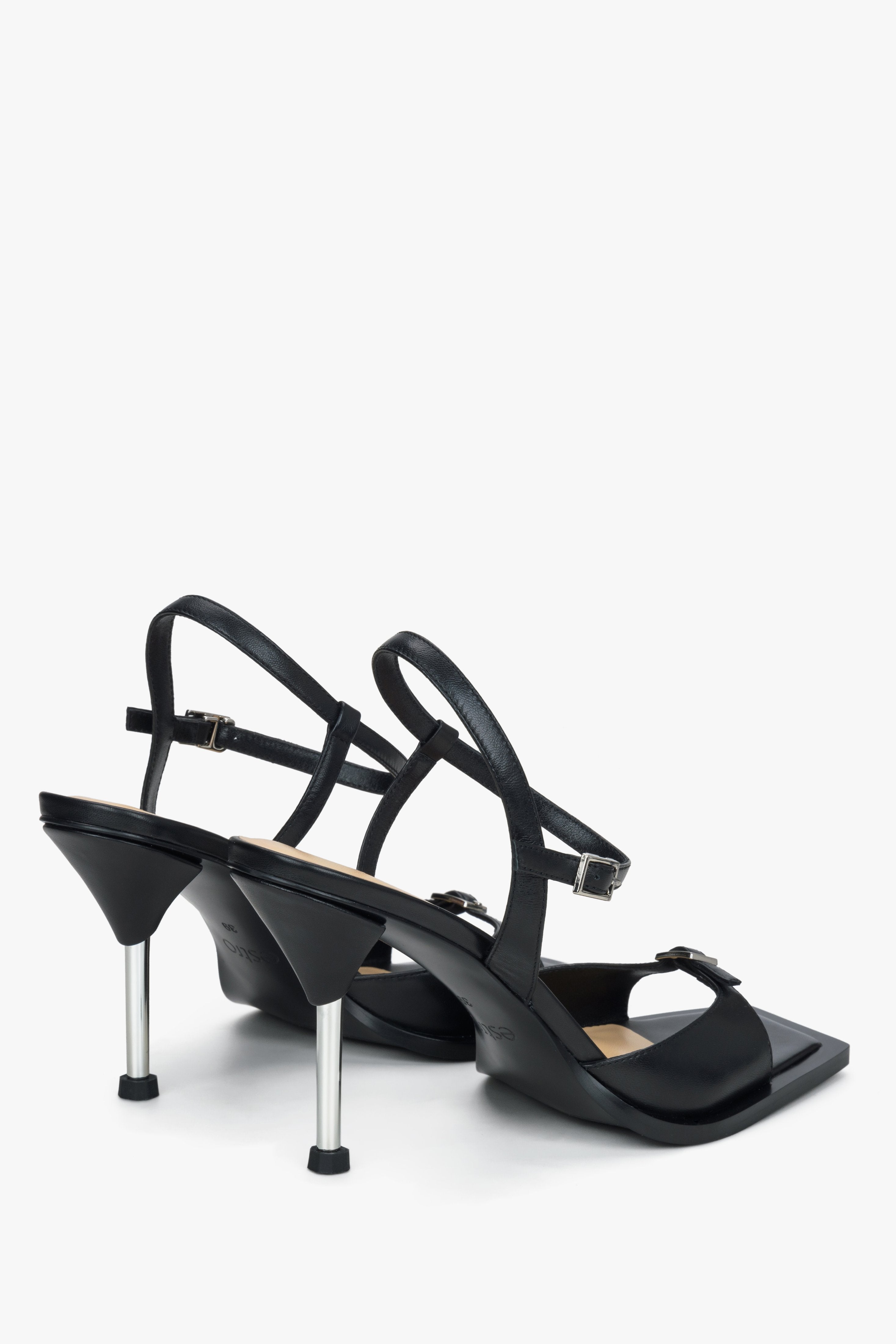 Rückwärtige Schrägansicht der schwarzen Stiletto-Sandaletten mit Fesselriemchen und glänzendem Absatz