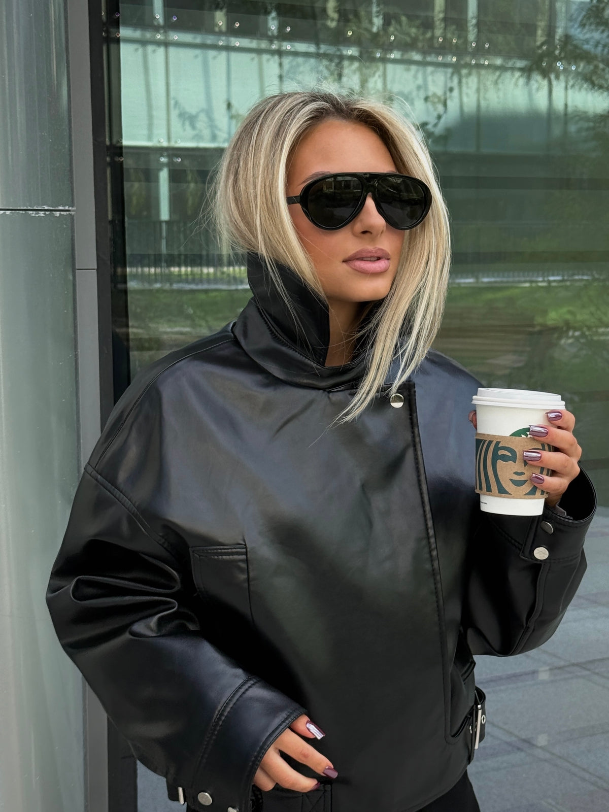Porträt-Aufnahme draußen mit blondem Model in der schwarzen Oversize-Bikerjacke und Sonnenbrille
