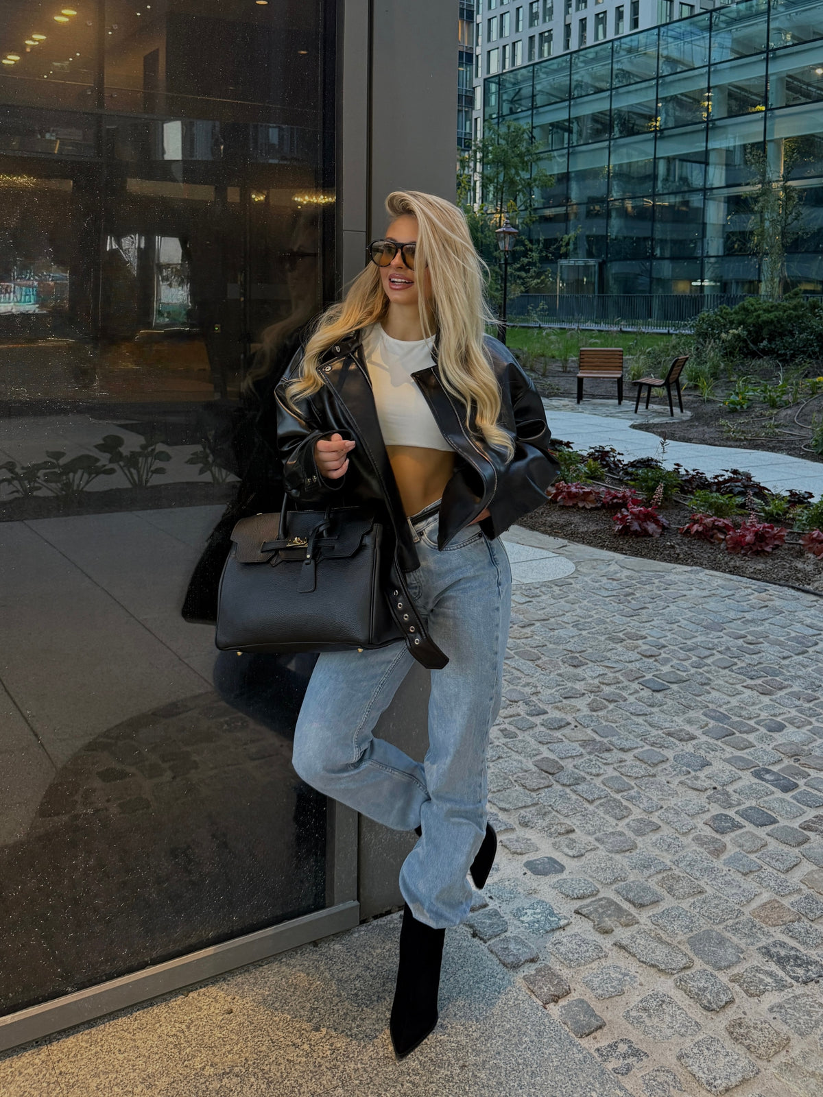 Ganzkörper-Lifestyle-Shot des Models mit der schwarzen Premium-Lederhandtasche