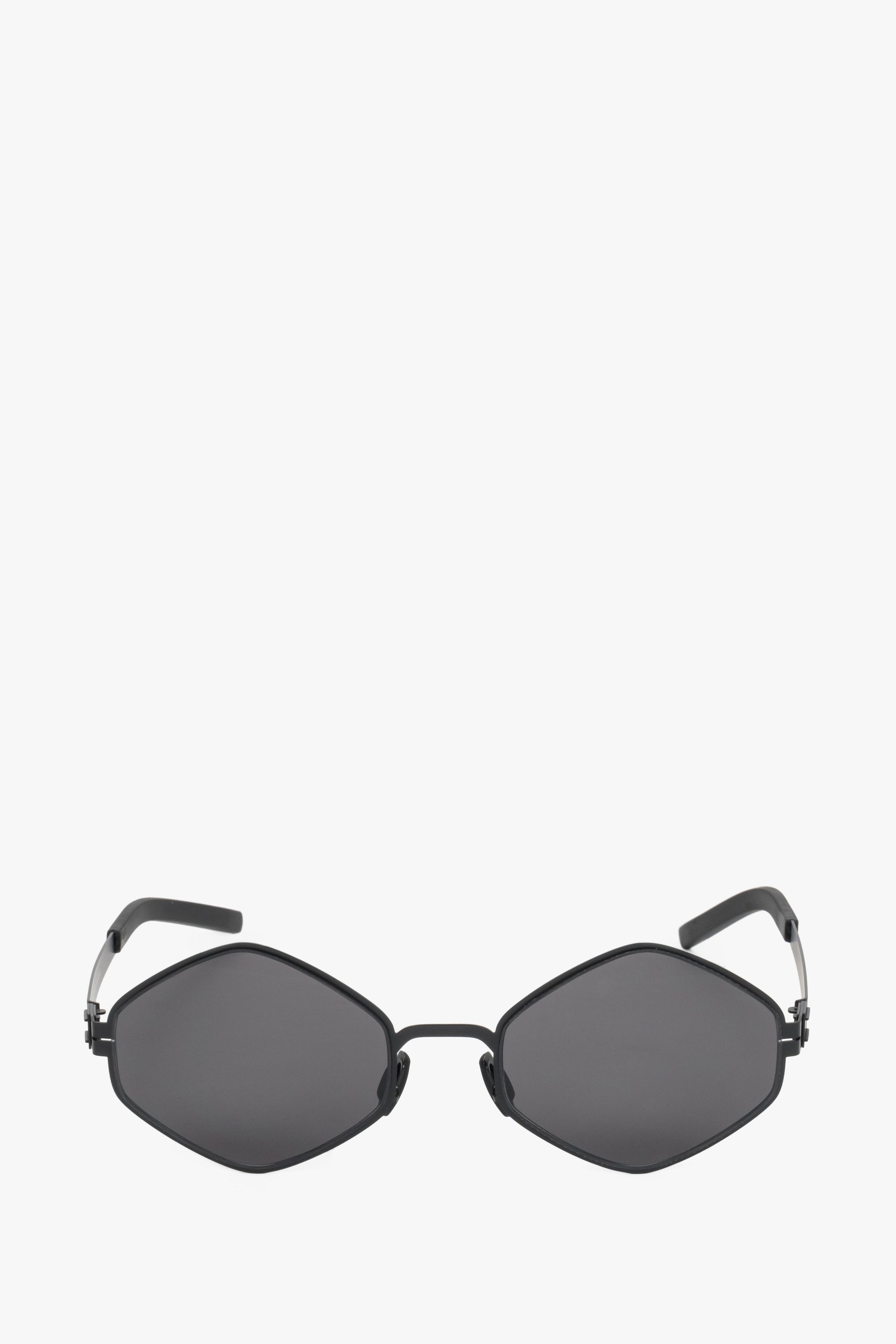 Frontale Ansicht der schwarzen Damen-Sonnenbrille mit markanter sechseckiger Form und dünner Fassung 