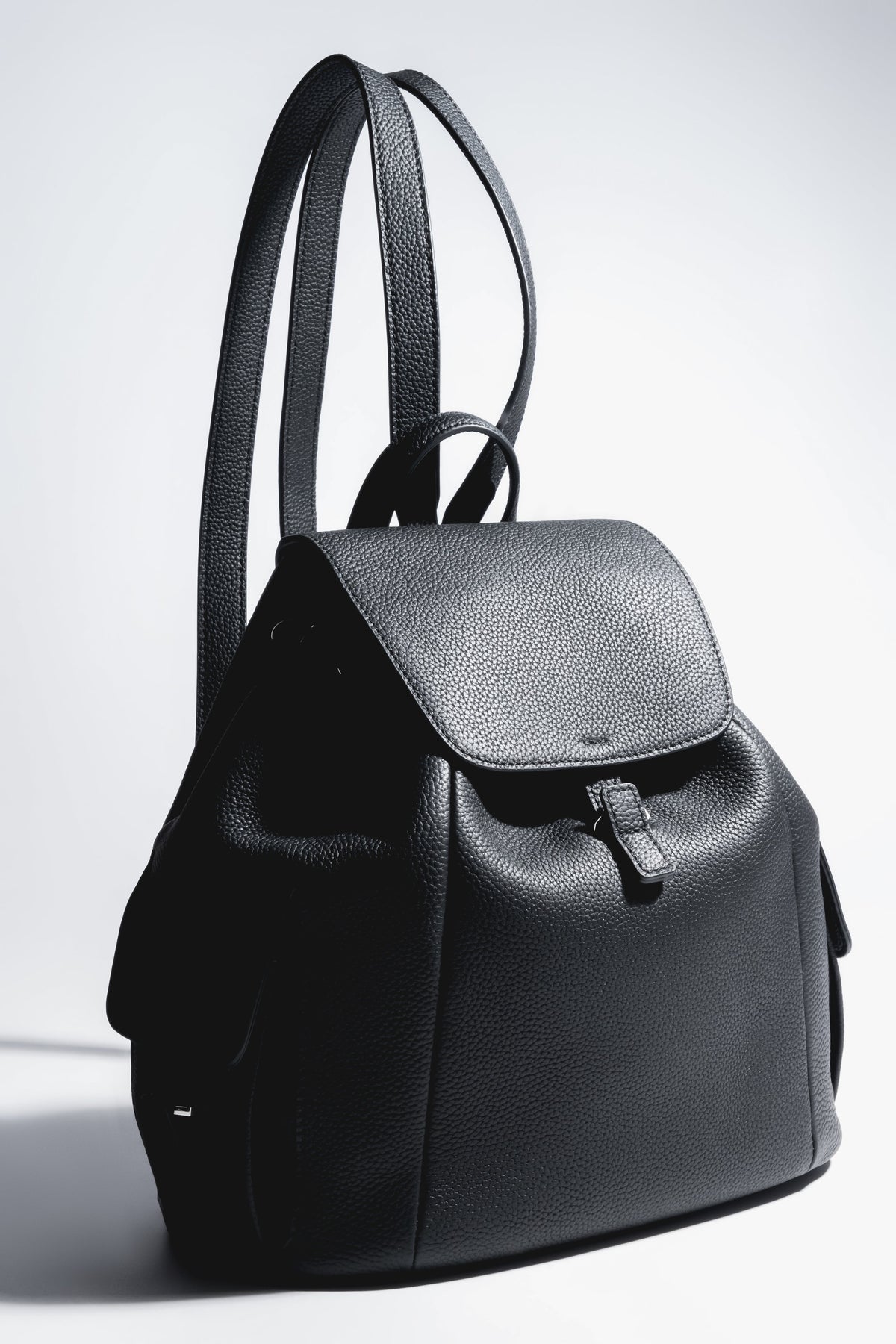 Künstlerische Profilansicht des schwarzen Damen-Beutelrucksacks aus genarbtem Leder