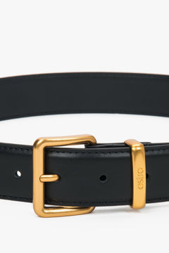 Nahaufnahme der eleganten, goldenen Dornschnalle und der Lederschlaufe mit Logo 
