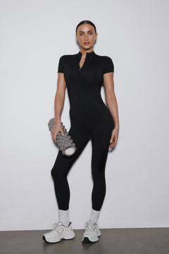 Ganzkörperansicht des schwarzen Damen-Sport-Jumpsuits mit kurzen Ärmeln und langen Beinen von vorne.