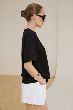Model im schwarzen Boxy-Fit T-Shirt aus Baumwolle und weißen Shorts