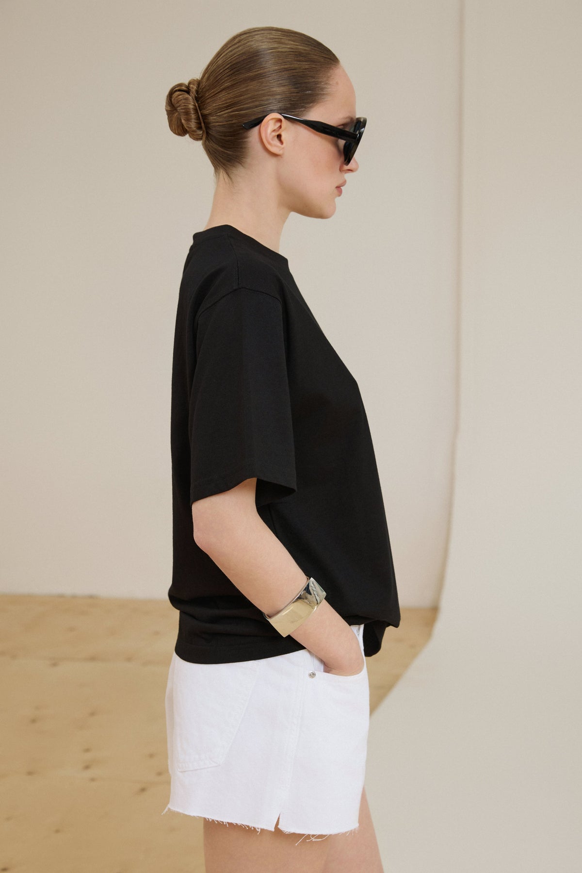 Model im schwarzen Boxy-Fit T-Shirt aus Baumwolle und weißen Shorts