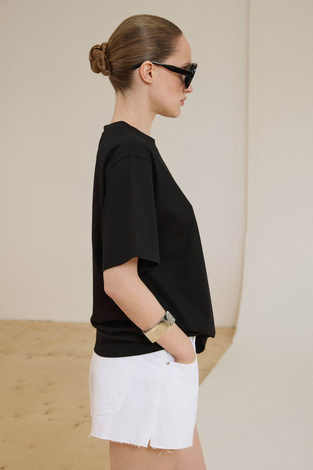 Model im schwarzen Boxy-Fit T-Shirt aus Baumwolle und weißen Shorts