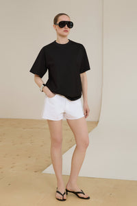 Vorderansicht des Models im schwarzen Oversize T-Shirt und weißen Shorts stehend