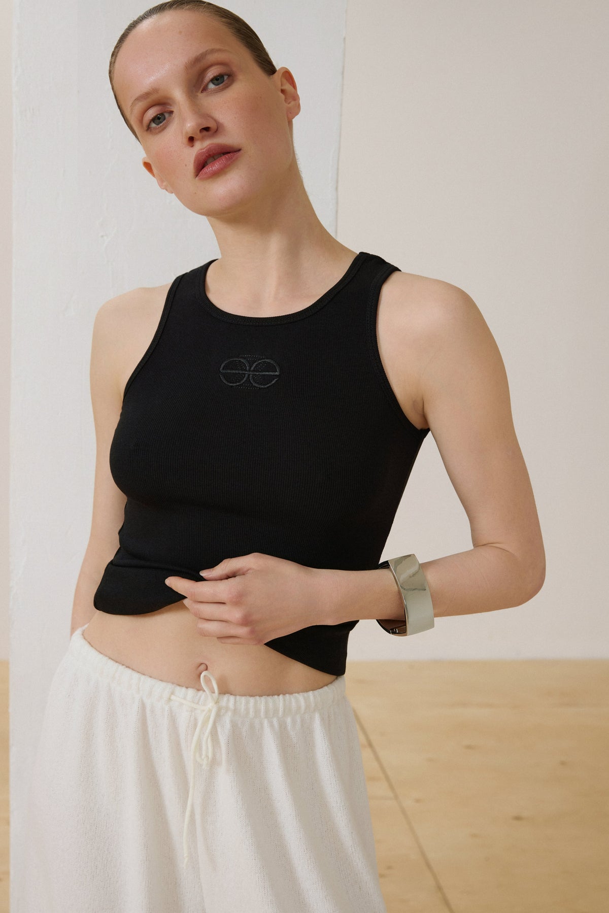 Model in schwarzem Slim-Fit Baumwoll-Top und weißer weiter Hose