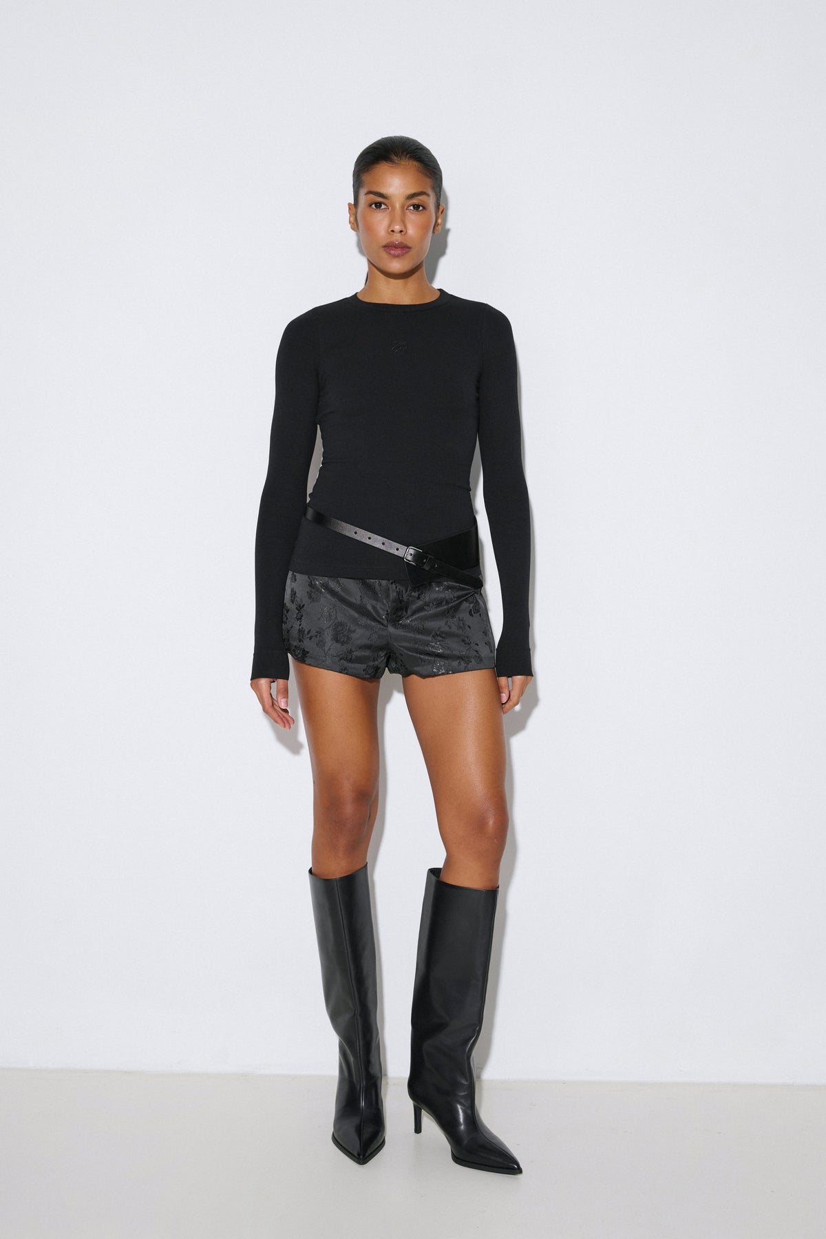 Studio-Aufnahme Ganzkörper: Model steht im figurbetonten schwarzen gerippten Longsleeve aus Baumwolle und Viskose