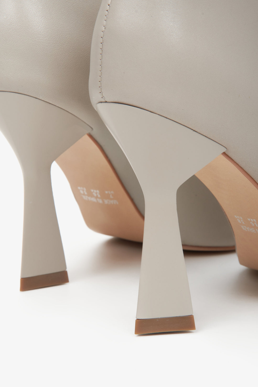 Lederne, hellgraue Damenstiefeletten Estro auf Stilettoabsatz – Nahaufnahme der Absatzlinie.