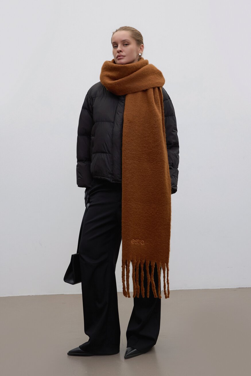 Lifestyle-Aufnahme eines Models in schwarzer Winterjacke und weiter Hose, das den voluminösen braunen Schal mit Fransen von Estro trägt