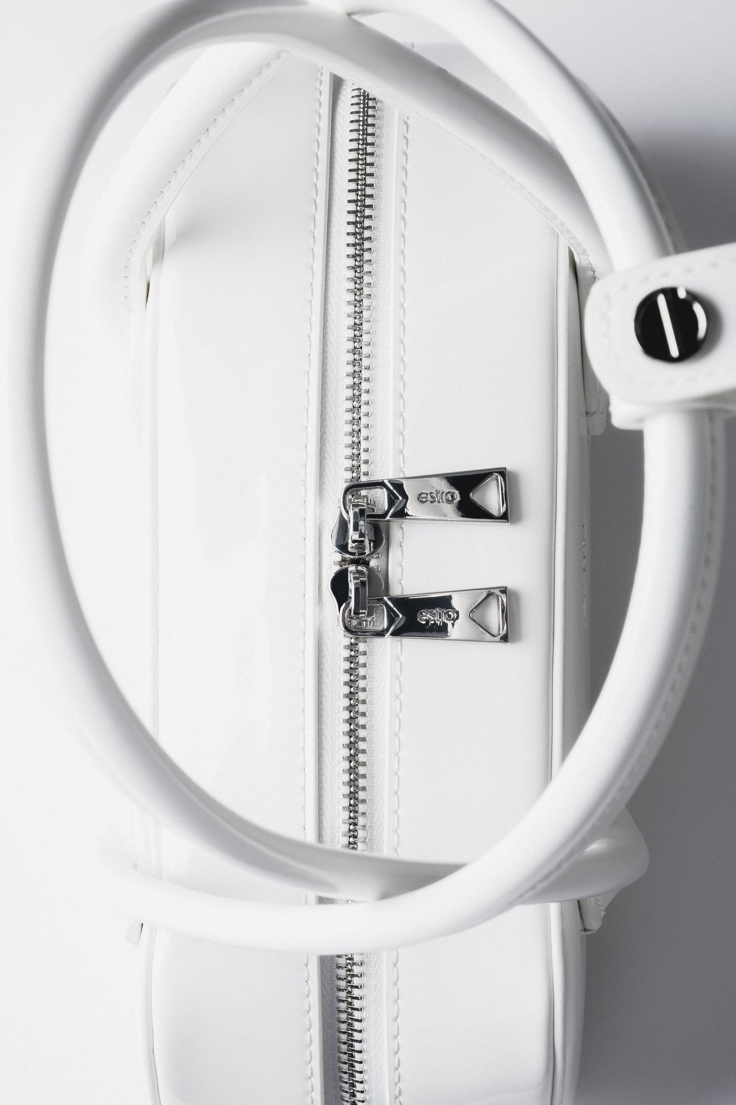 Detailaufnahme des Pins mit Markenlogo an den Tragegriffen der Tasche.