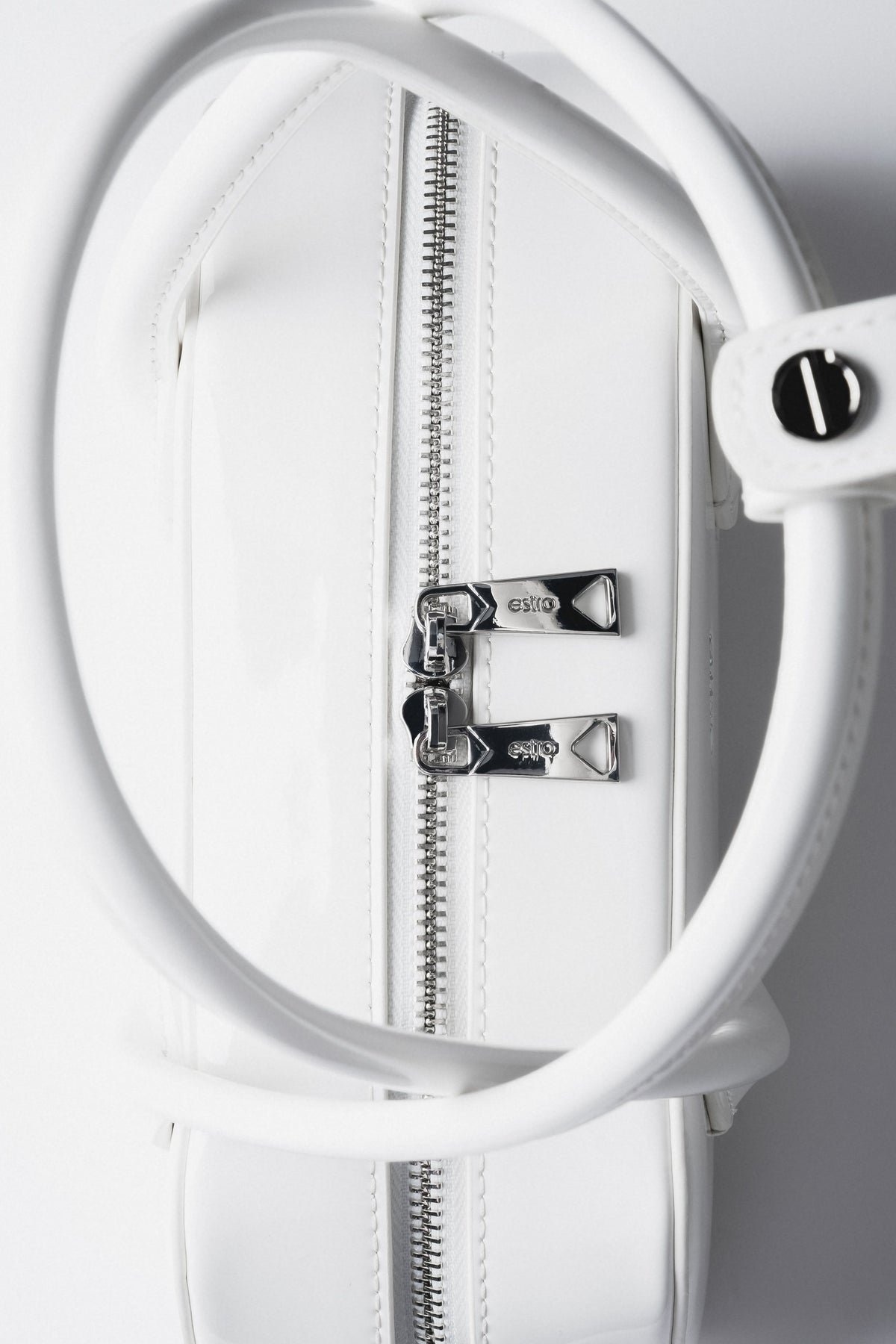 Detailaufnahme des Pins mit Markenlogo an den Tragegriffen der Tasche.