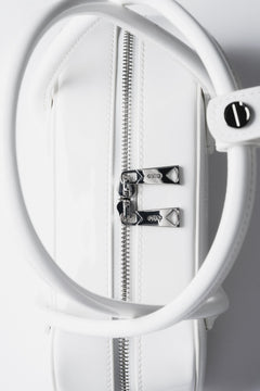 Detailaufnahme des Pins mit Markenlogo an den Tragegriffen der Tasche.