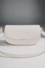 Weiße Damen-Schultertasche aus Leder in Hufeisenform auf grauem Hintergrund.