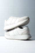 Zwei gestapelte weiße Damen-Sneaker aus weichem Echtleder und Velours.
