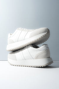 Zwei gestapelte weiße Damen-Sneaker aus weichem Echtleder und Velours.