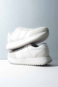 Zwei gestapelte weiße Damen-Sneaker aus weichem Echtleder und Velours.