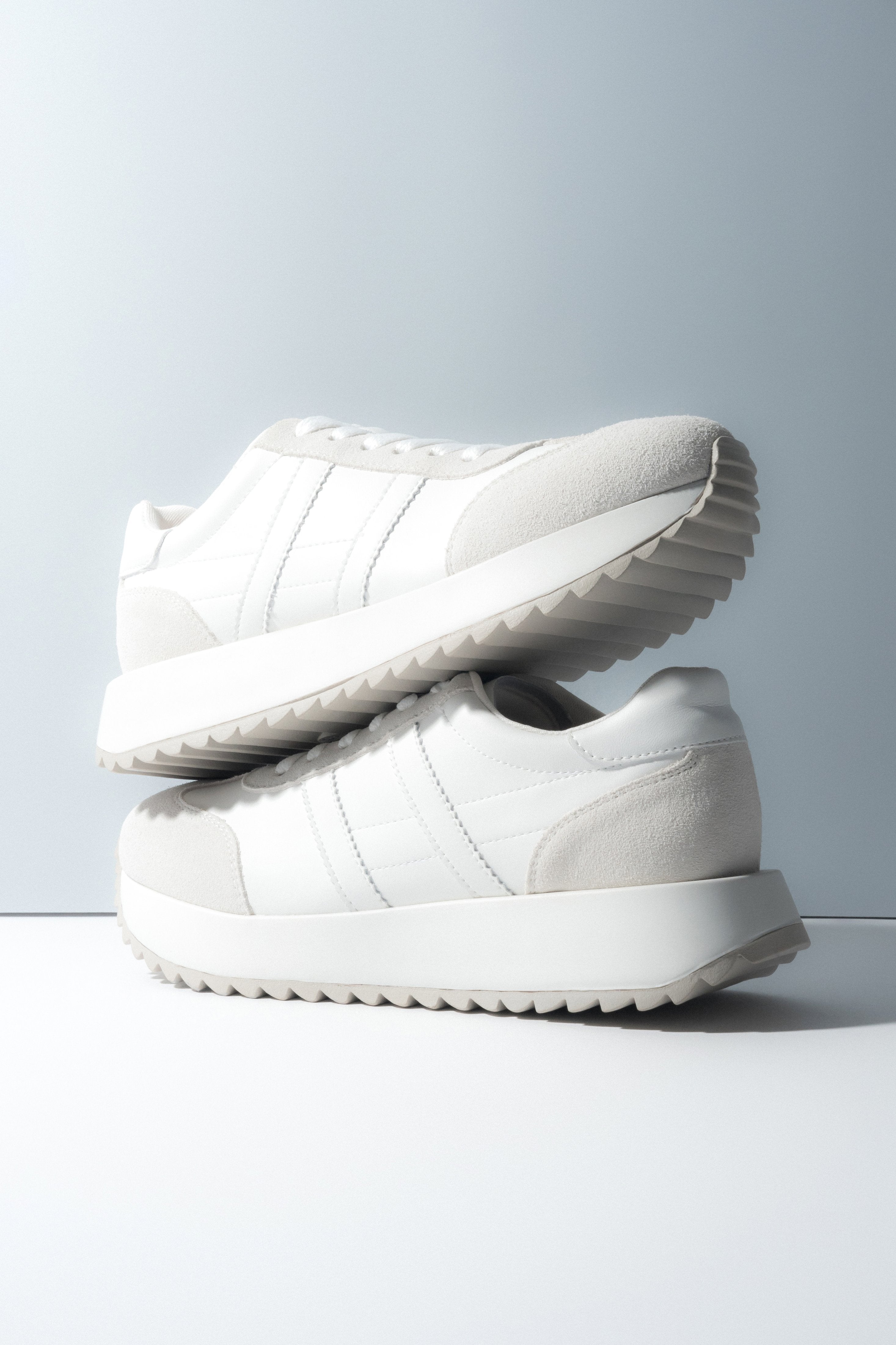 Zwei gestapelte weiße Damen-Sneaker aus weichem Echtleder und Velours.