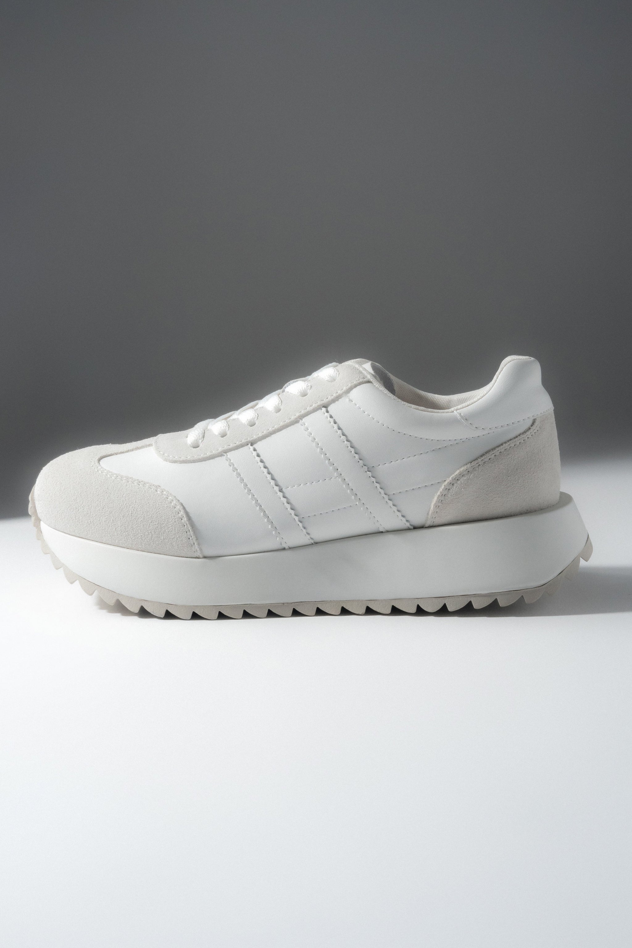 Leicht schräge Seitenansicht des weißen Sneakers mit Schnürung.
