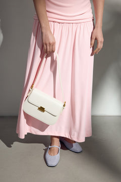 Model im rosa Kleid trägt die elegante weiße Schultertasche von Estro.