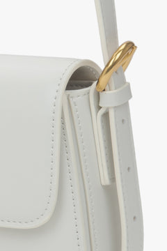 Nahaufnahme der goldfarbenen Beschläge an der weißen Damen-Tasche.