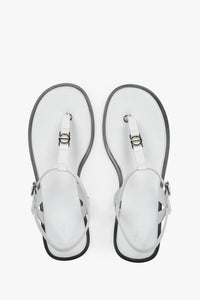 Draufsicht auf die weißen Zehentrenner-Sandalen aus Leder mit silbernen Details und dunkler Sohlenkante