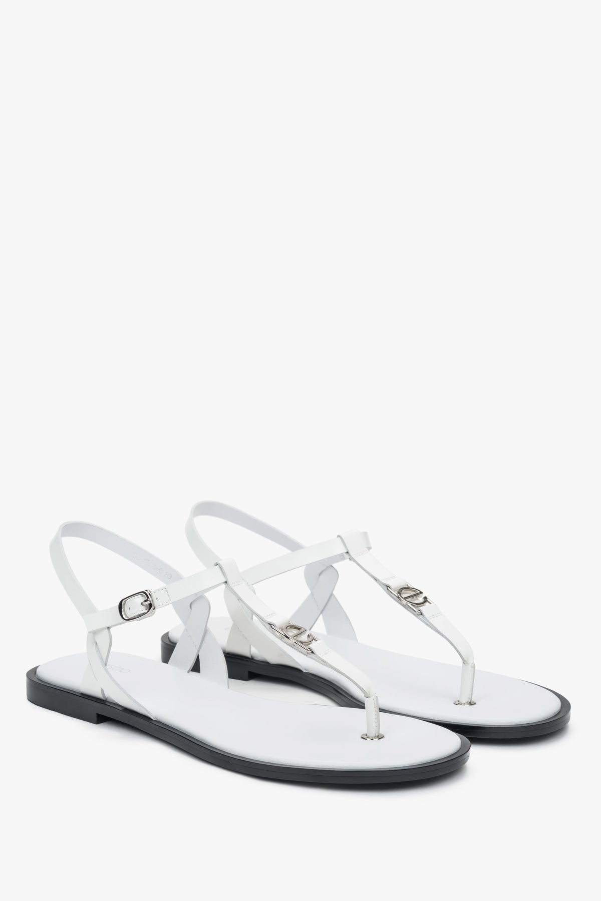 Schrägansicht des Paares weißer Leder-Sandalen mit feinem Fesselriemchen